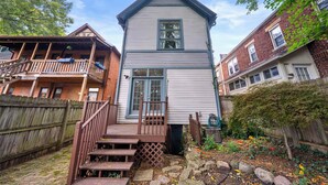 A two-story house with a wooden deck and a small garden. - High Street Hideaway - For 8 (Columbus)