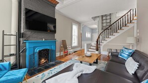 A living room with a fireplace, a sofa, a coffee table, and a staircase. - High Street Hideaway - For 8 (Columbus)