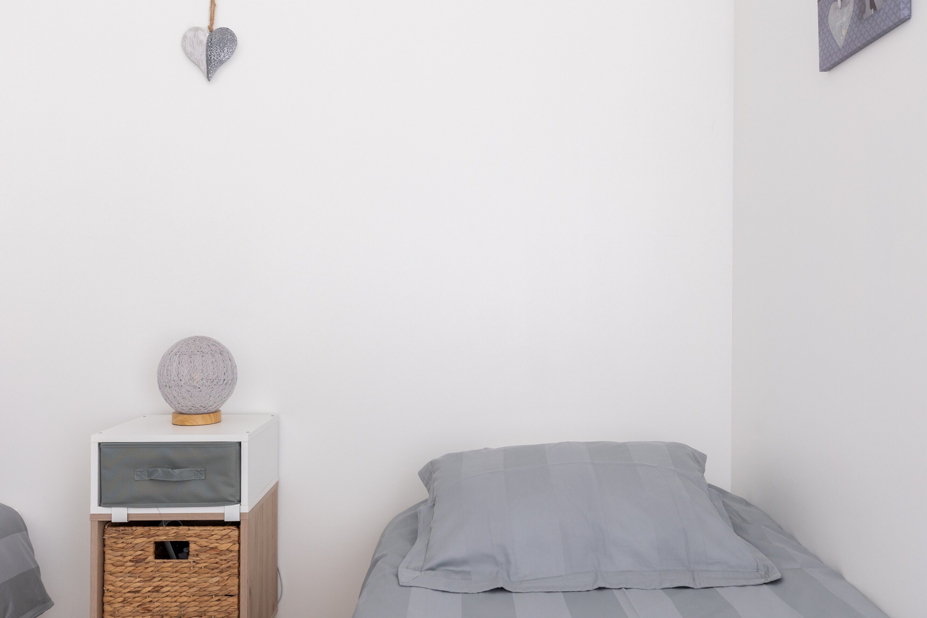 Un dormitorio con cama, mesita de noche con lámpara y estante en la pared.