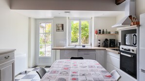 A compact kitchen with a dining area, a window with a view, and a microwave. - 5 Minutes from Amboise in the Heart of the Châteaux (Limeray)