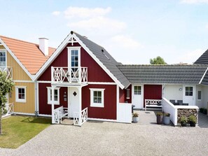A red barn-style building with a balcony, white railings, and a gravel driveway. - 4 Star Holiday Home in Brenderup Fyn (Middelfart)