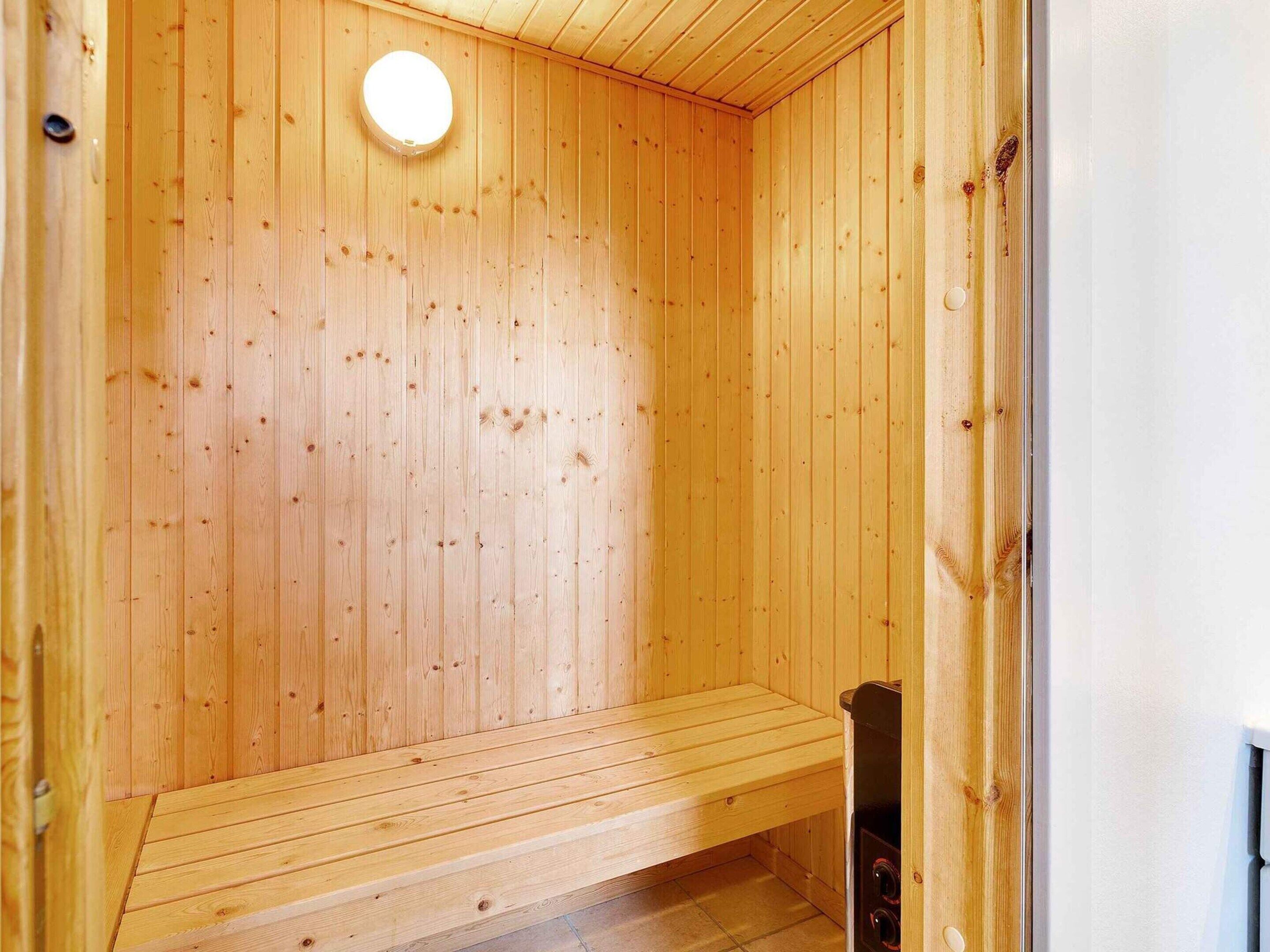 Una sauna de madera con un banco y una lámpara circular en el techo.