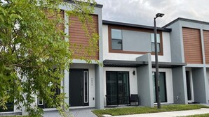A modern building with a flat roof, large windows, and a small outdoor seating area. - 3 bedrooms house 12 minutes to Disney (Kissimmee)