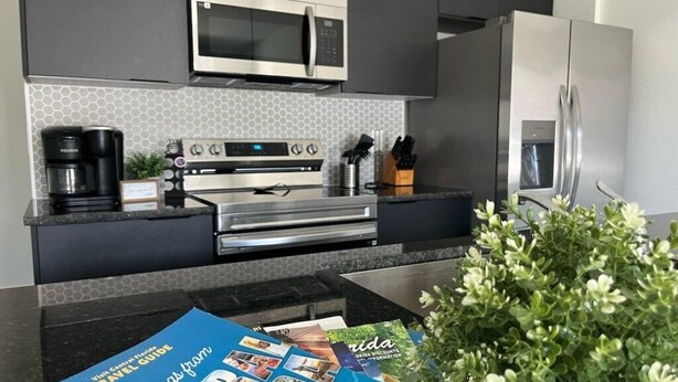 A modern kitchen with a microwave, oven, and refrigerator. There is a coffee maker and a plant on the counter. - 3 bedrooms house 12 minutes to Disney (Kissimmee)