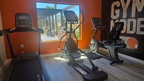 A gym with a treadmill, elliptical, and stationary bike.