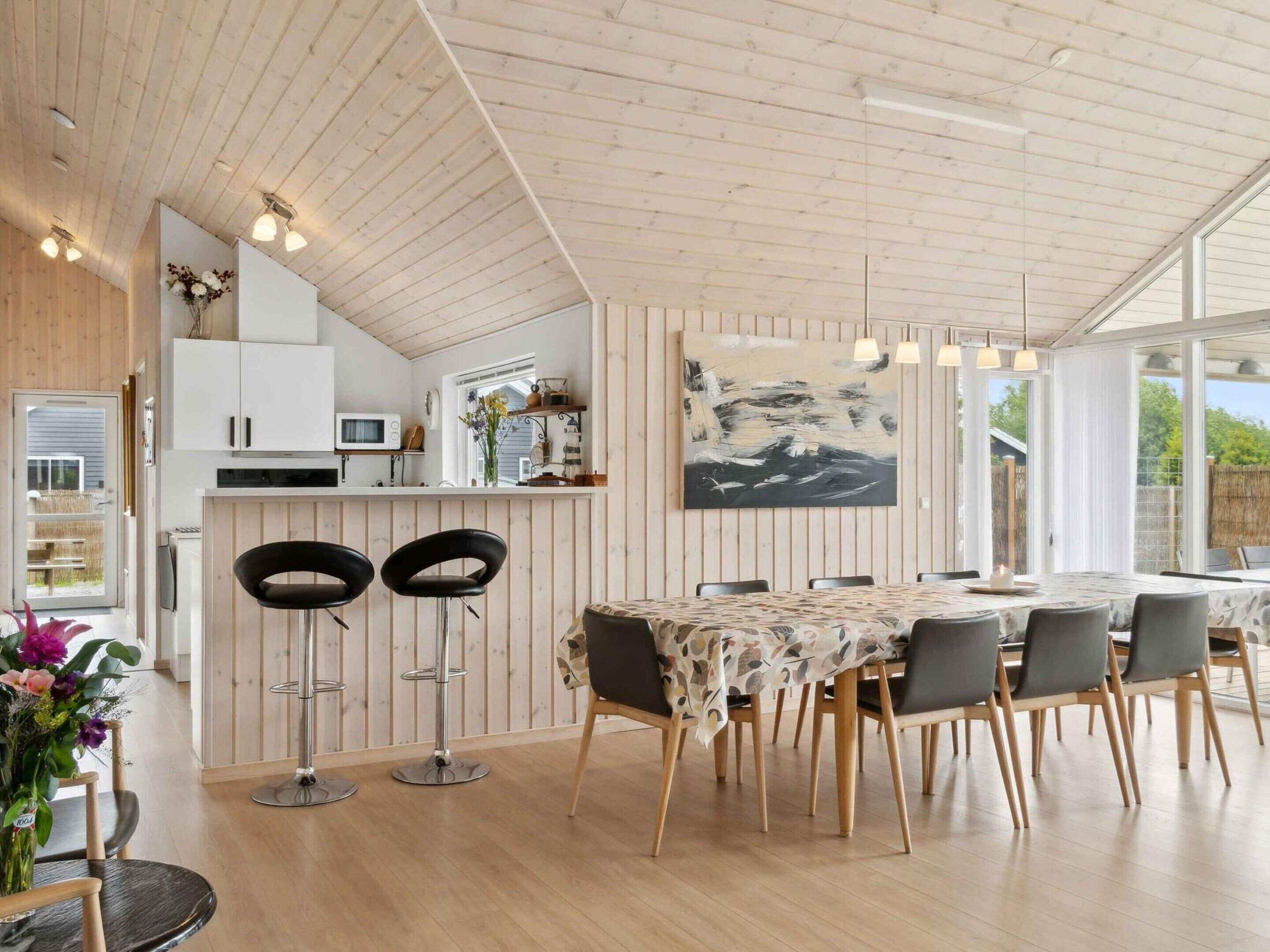 Een moderne keuken met houten kastjes, een magnetron en een eethoek met een tafel en stoelen.