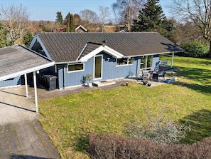 Een blauw huis met een schuin dak, een overdekte patio en een kleine tuin.