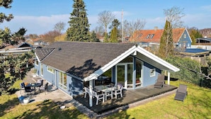 A blue house with a sloped roof, a patio with outdoor furniture, and a well-maintained lawn. - 5 Star Holiday Home in Vordingborg (Vordingborg)
