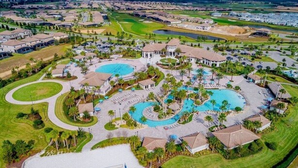 Vista aérea de um resort com várias piscinas, áreas ajardinadas e edifícios residenciais.