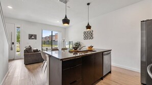 Una cocina moderna con una isla central, lavavajillas integrado e iluminación colgante.