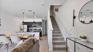 Un interior moderno con una escalera, un comedor y una cocina.