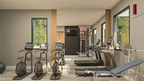 Un gimnasio moderno con cintas de correr, elípticas y un banco.