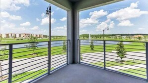 Un balcon donnant sur un parc verdoyant et sur des bâtiments situés de l’autre côté d’une étendue d’eau.