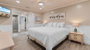 Ein Schlafzimmer mit einem großen Bett, einem Nachttisch mit Lampe, einem Deckenventilator und einem Bild an der Wand.