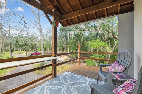 Un espace extérieur abrité, doté d’une terrasse en bois, d’un banc et d’une table.