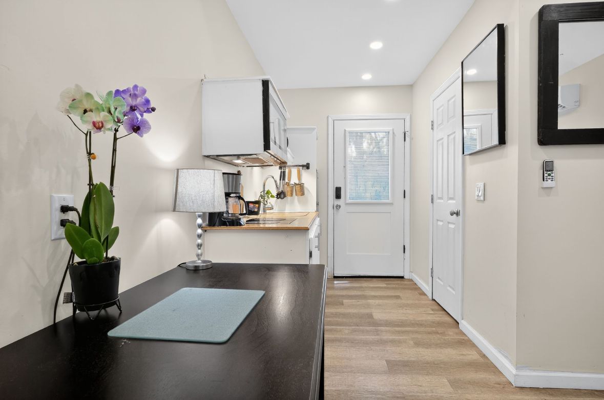 A modern kitchen with white cabinets, a black countertop, and a potted orchid.