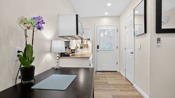 A modern kitchen with white cabinets, a black countertop, and a potted orchid.