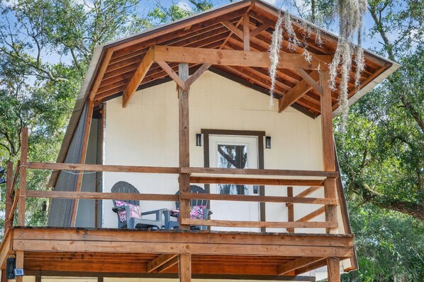 A wooden cabin with a porch and a covered deck area.