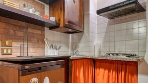 A kitchen with a brick wall, wooden cabinets, a stainless steel range hood, and a tiled backsplash. - GuestHost - Comfortable apartment of approximately 45 square meters, perfect for a stay of two, located on the ground floor of a period building (accessible via a few steps).The property is located in Bagnaia, a quiet hamlet a few kilometers from Perugia (Bagnaia)