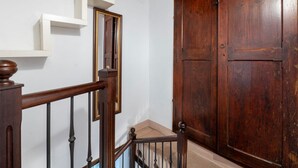 A wooden staircase with a handrail, a white wall, and a large wooden door. - GuestHost - Comfortable apartment of approximately 45 square meters, perfect for a stay of two, located on the ground floor of a period building (accessible via a few steps).The property is located in Bagnaia, a quiet hamlet a few kilometers from Perugia (Bagnaia)