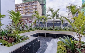 Un edificio moderno con jardín en la azotea, que incluye diversas plantas y una pequeña fuente.