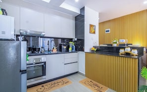 Una cocina moderna con armarios blancos, encimera negra y una pared decorativa de madera.