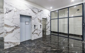 Un pasillo con paredes de mármol y una puerta de cristal.