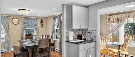 A modern kitchen with a central island, wooden dining table, and chairs.