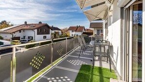 A balcony with a table and chairs, a covered area, and a view of neighboring houses. - Attic Apartment with Air Conditioning in Freilassing (Freilassing)