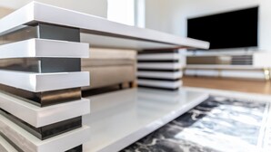 A modern living room with a flat-screen TV, a stack of books, and a marble-patterned rug. - Attic Apartment with Air Conditioning in Freilassing (Freilassing)