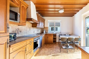 Une cuisine dotée de meubles en bois, d’un four à micro-ondes, d’un grille-pain et d’un coin repas avec des chaises et une table.