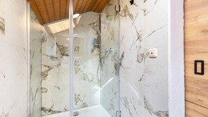 Een glazen douchecabine met marmeren wanden en een houten plafond.