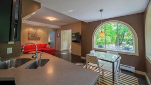 A modern kitchen with a large island, a dining area with a glass table, and a view through a large window. - 2 Unit house across from the hospital (Antigonish)