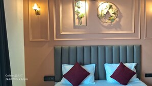 A hotel room with a bed, two wall-mounted light fixtures, and a decorative mirror. - Luxury Rooms In Lucknow (Lucknow)