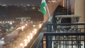 A balcony with a view of a city street at night, featuring a flag and a railing. - Luxury Rooms In Lucknow (Lucknow)