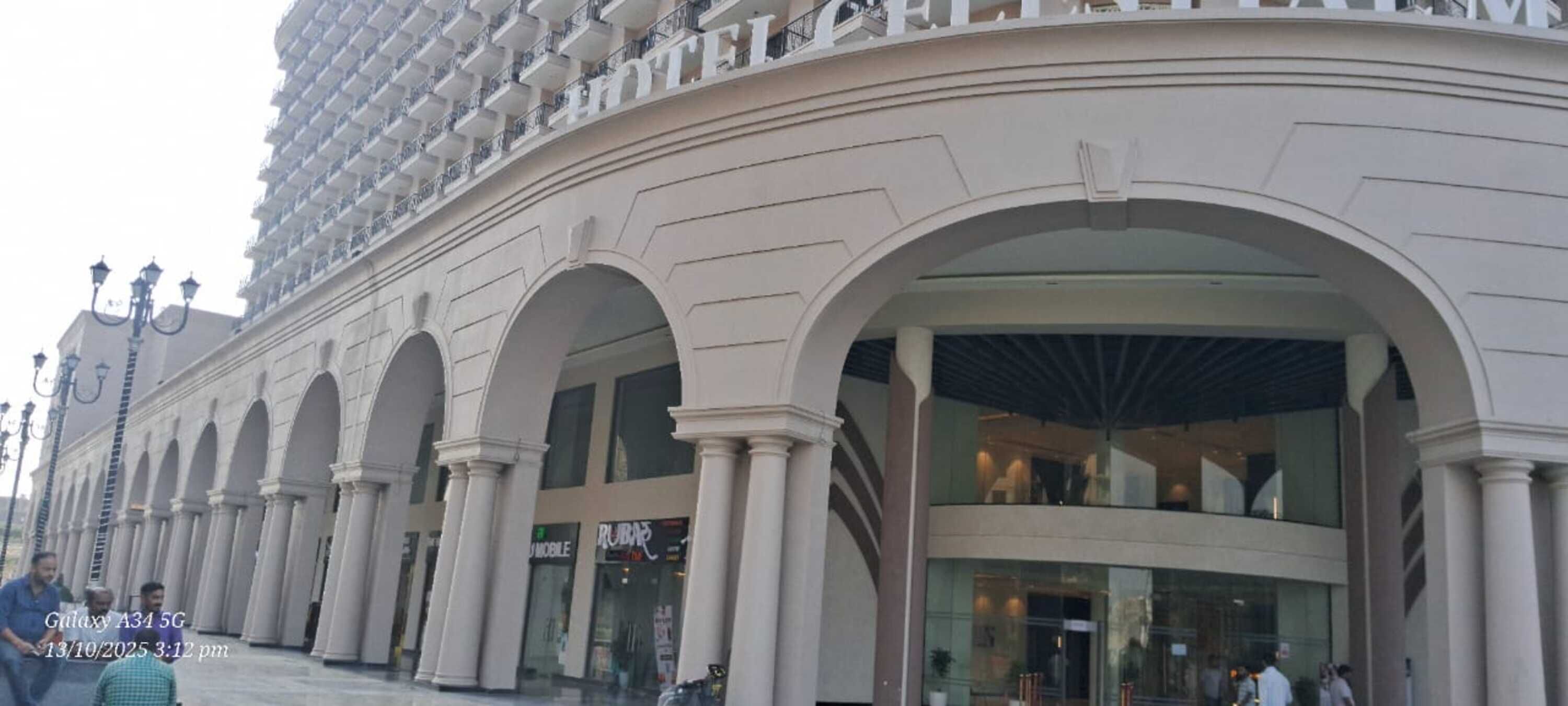A hotel with a modern facade, featuring a curved entrance with large arches and a prominent balcony area.