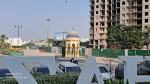 A view of a cityscape with a large, unfinished building, a roundabout, and parked cars. - Luxury Rooms In Lucknow (Lucknow)