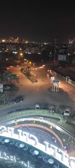 A nighttime aerial view of a cityscape with a roundabout, a central dome structure, and a circular plaza with seating. - Luxury Rooms In Lucknow (Lucknow)