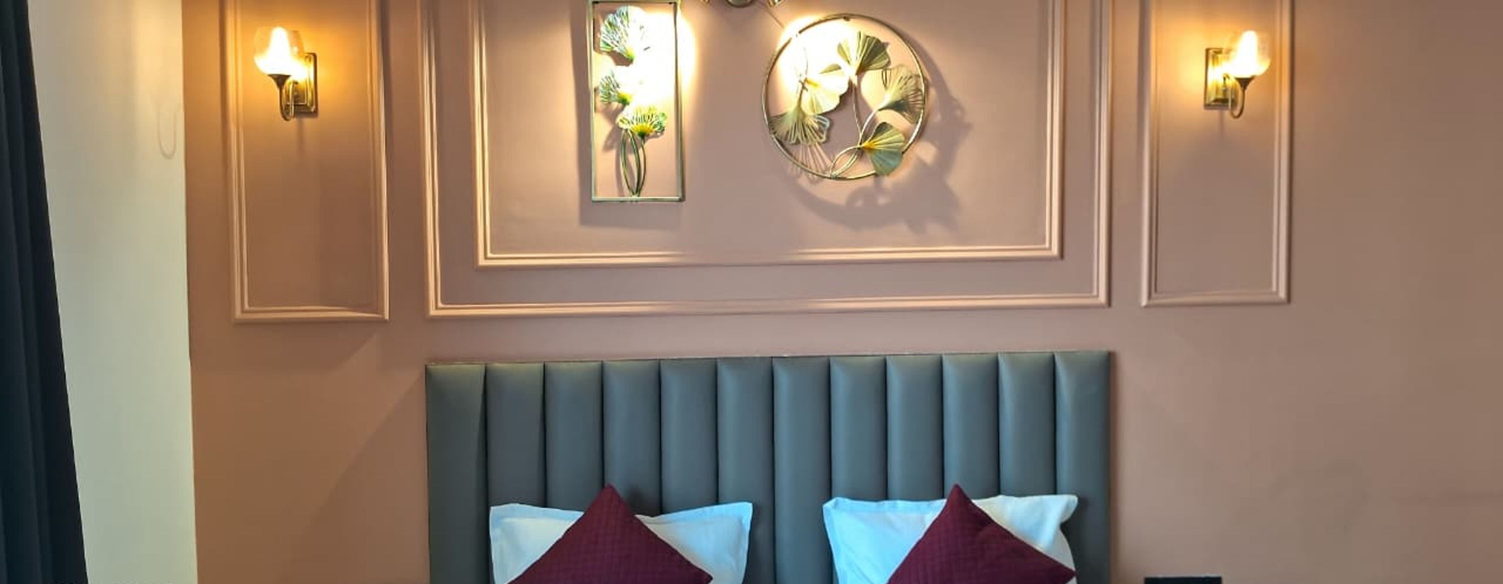 A hotel room with a bed, two wall-mounted light fixtures, and a decorative mirror.