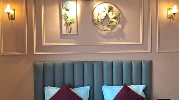 A hotel room with a bed, two wall-mounted light fixtures, and a decorative mirror.