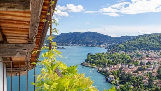 Une vue sur un lac, avec une ville en arrière-plan, le tout étant entouré de collines.