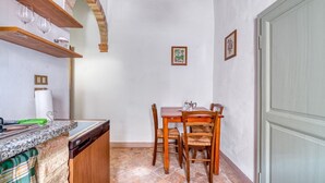 Una cocina con una mesa de comedor, sillas, una encimera con un lavabo y una puerta.