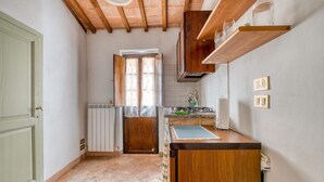 Una cocina compacta con techo de madera, una ventana, un radiador y una encimera con un lavamanos.