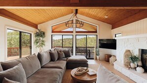 A spacious living room with a large sectional sofa, a fireplace, and a TV mounted on the wall. - Luxury by Nature - Sedona Designer Retreat (Sedona)