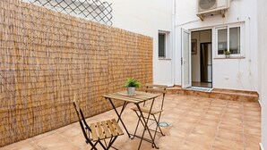 Eine Terrasse mit einer Bambuswand, einem Tisch mit einer Pflanze und einem Stuhl.