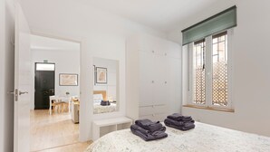 Ein Schlafzimmer mit einem Bett, einem Schreibtisch, einem Sessel, einer Bank und einem Fenster mit Aussicht.