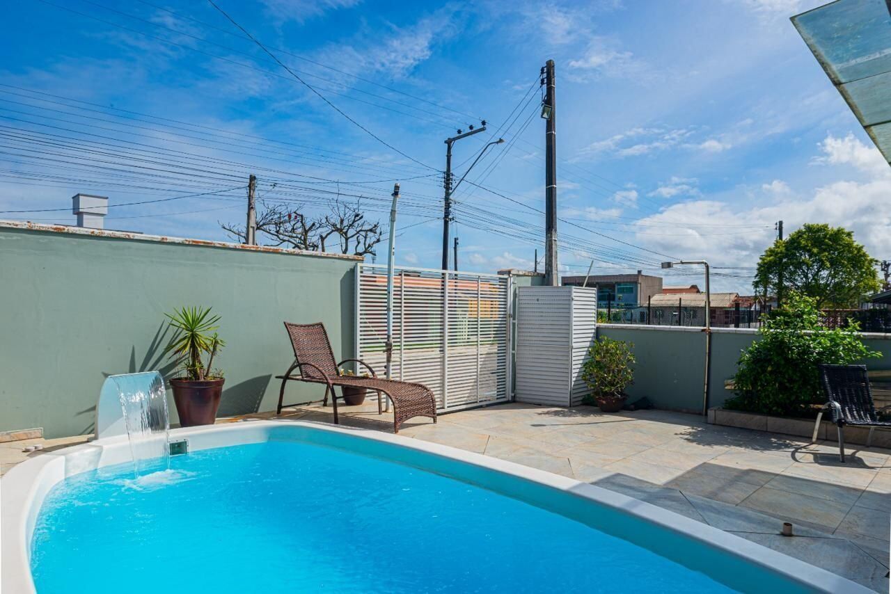 Une piscine agrémentée d’un élément décoratif aquatique, entourée d’une terrasse avec des chaises et des plantes en pot.