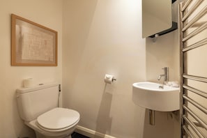 A small bathroom with a toilet, a sink, and a framed artwork on the wall. - Chiswick Courtyard House (London)