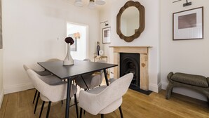 Un comedor con una mesa y sillas, una chimenea y un espejo en la pared.