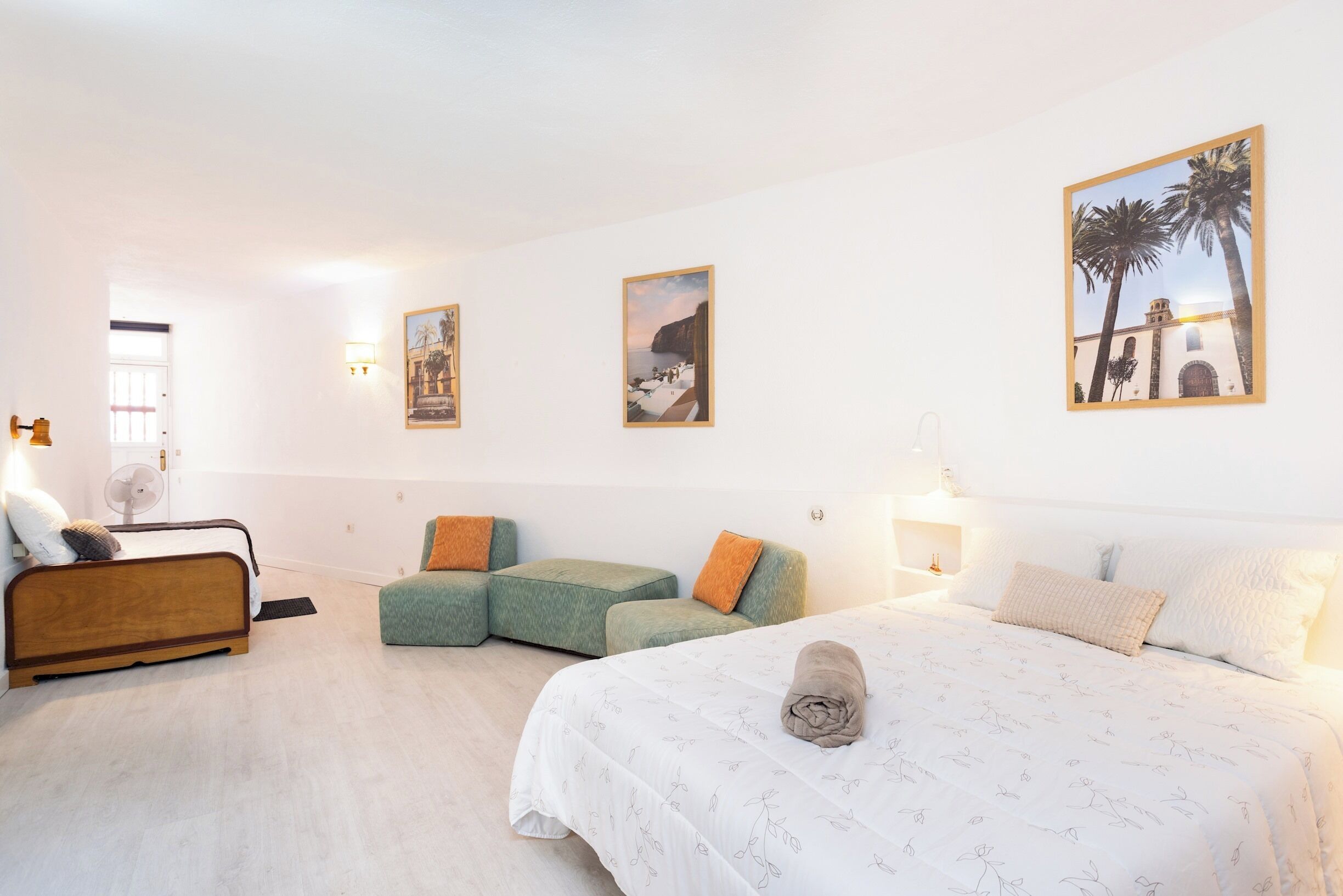 Une chambre à coucher comprenant un lit, un canapé, un fauteuil et des œuvres d’art accrochées aux murs.